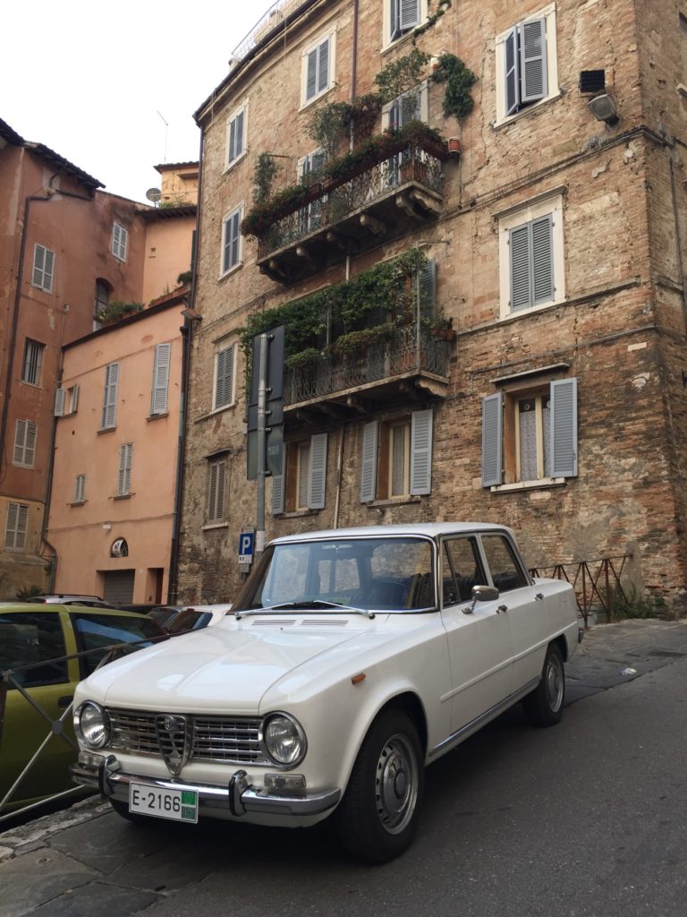 The Alfa Romeo in front of the hotel, parked on the street.